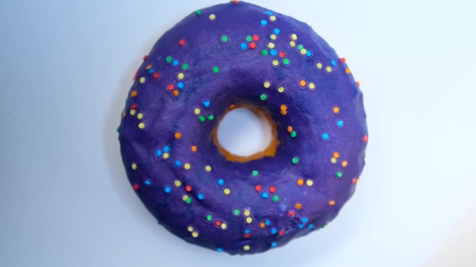 近距离，甜甜圈与蓝莓糖霜与彩色洒落旋转在白色背景顶部视图。
