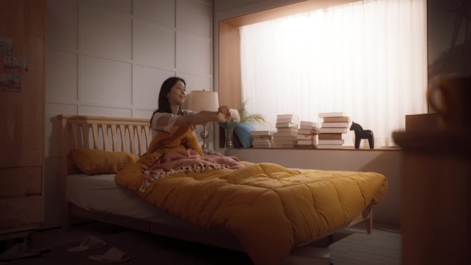 放大美丽的韩国女人的肖像，早上醒来，伸展，阳光从公寓的窗户照进卧室，为商业成就做好准备。广角镜头