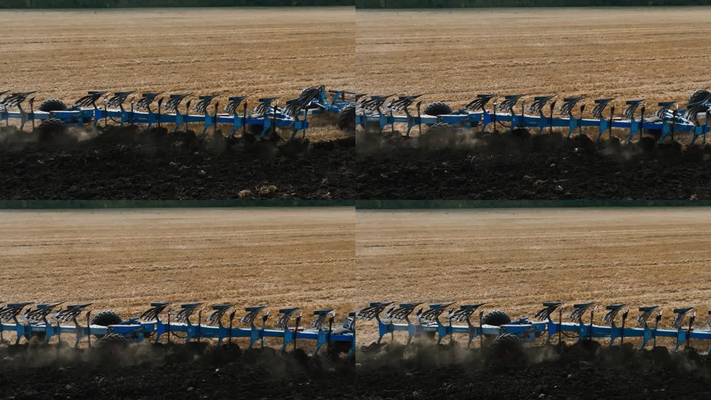 在田地里，在拖拉机后面移动的有支撑轮的可逆犁。耕地是为了播种。高生产力的反向犁工作在慢动作。农业，为