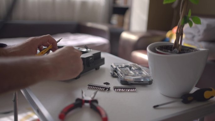 一个男人在家修理一些电子产品。生命中的一天。
