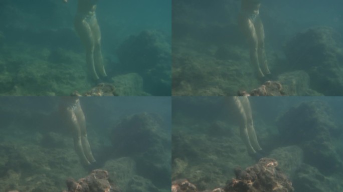 一个戴着面具的女人在水下勉强保持平衡，踮着脚尖站在一块大石头上。