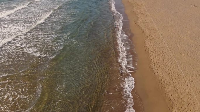 鸟瞰透明的蓝色大海，在夏天阳光明媚的日子里有美丽的海浪。热带景观从空气的海洋与蔚蓝的水，在日落沙底。