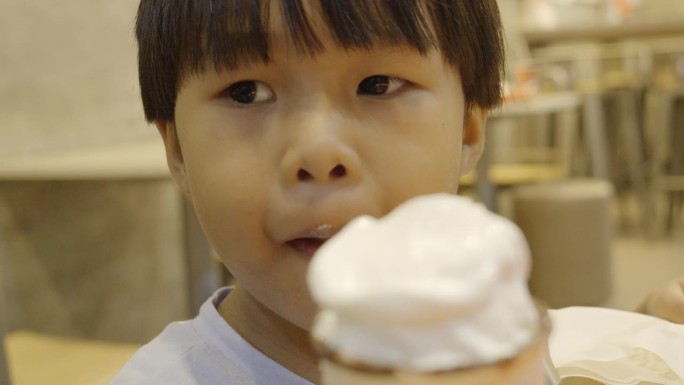 亚洲男孩开心地吃着巧克力甜筒。