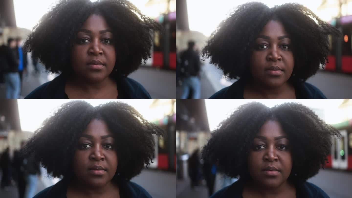 冬天，年轻的非洲女子在公交车站等车，她在镜头前看起来很严肃，背景是城市