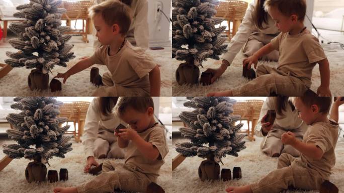 妈妈和她的小儿子在家里木马旁边的一棵小人造圣诞树旁玩耍。孩子在圣诞树旁玩木制玩具
