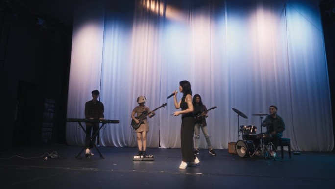 年轻的亚洲多种族组合女歌手现场乐队在舞台上表演