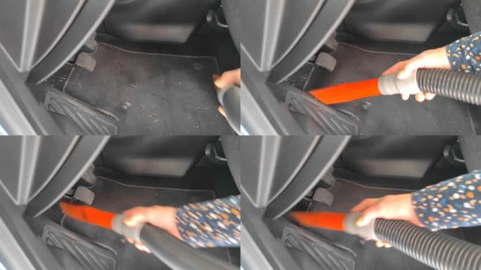 一名无法辨认的白人妇女在洗完一辆无法辨认的汽车后，用吸尘器清洁方向盘下的地垫