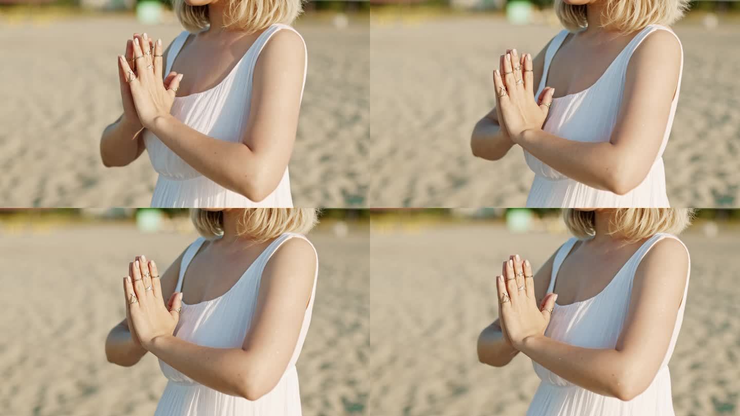 夏日日落时分，一名女子独自在沙滩上练习瑜伽，合掌感恩手印。穿白裙子的女孩。宗教，纯洁，顺从，灵性概念