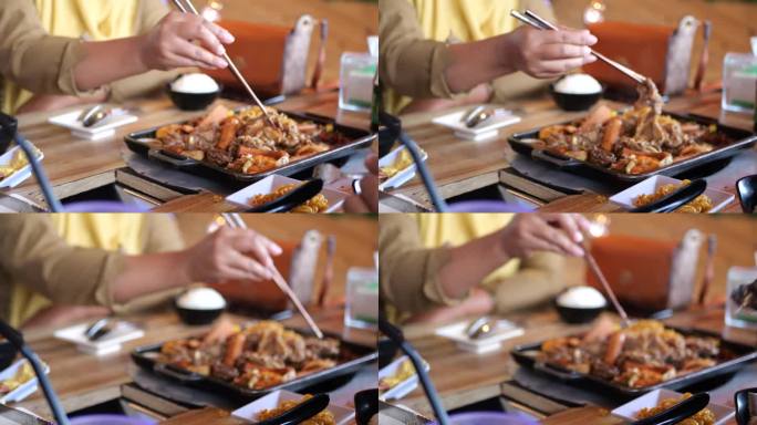 烹饪美味的日本食物suki涮和烧烤盘或烧烤盘。火锅涮的特写，用筷子夹肉、牛肉片放入火锅锅中烹煮。