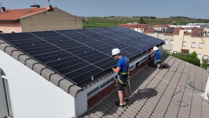 鸟瞰图太阳能团队在太阳能发电站工作，屋顶的房子里穿着蓝色的衣服