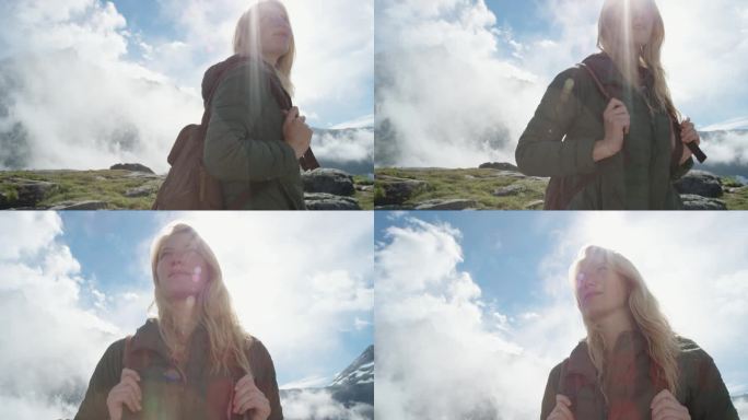 在山顶上的女人的特写肖像，金色的头发在风中吹过云层，在挪威慢动作观看徒步旅行者女孩