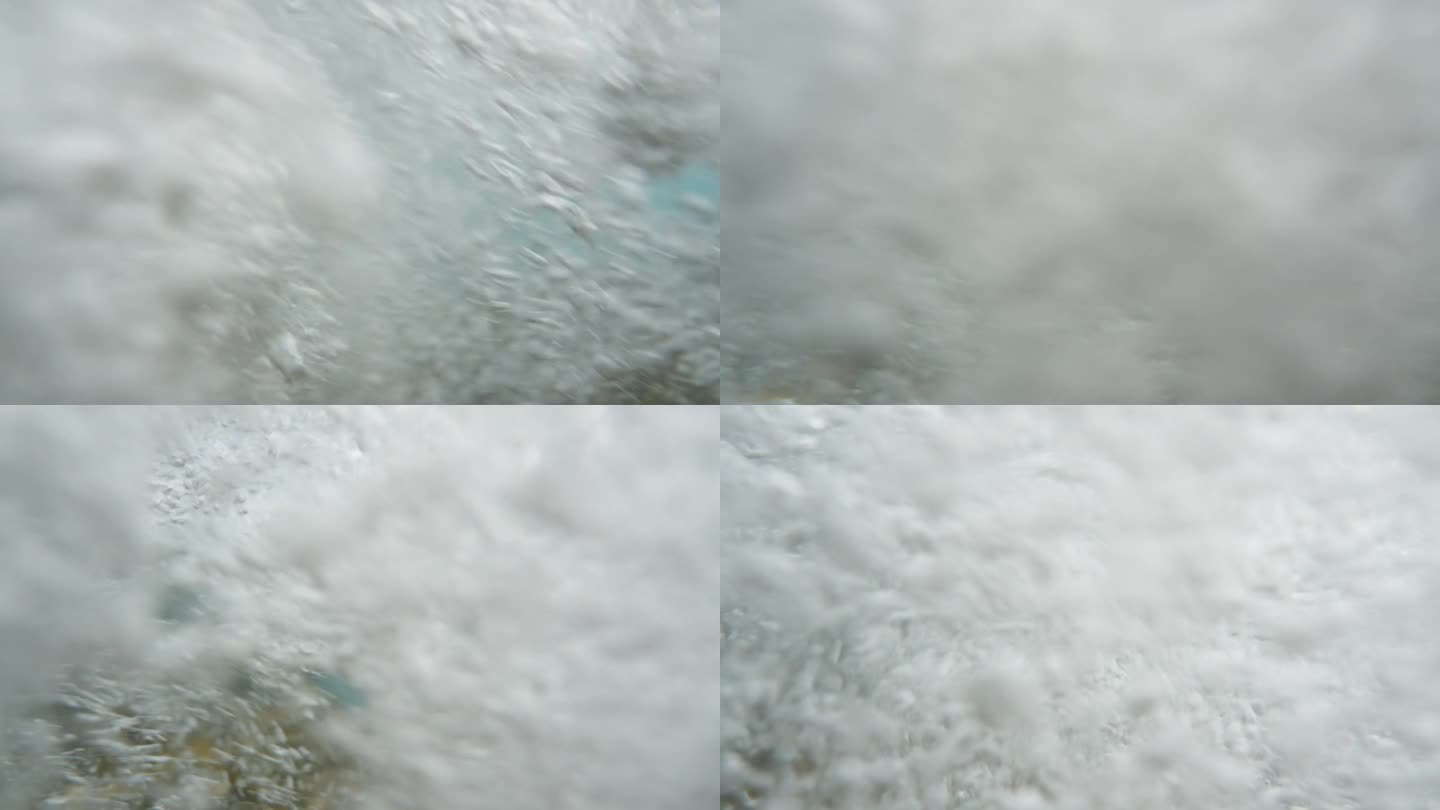 一个海浪的特写镜头，透明的水覆盖了相机，气泡在整个画面中出现，以慢动作。
