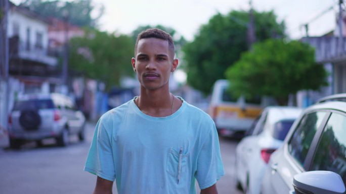 一个沉思的巴西黑人年轻人走在街上，凝视着沉思。一个深思熟虑的南美人正在向前走