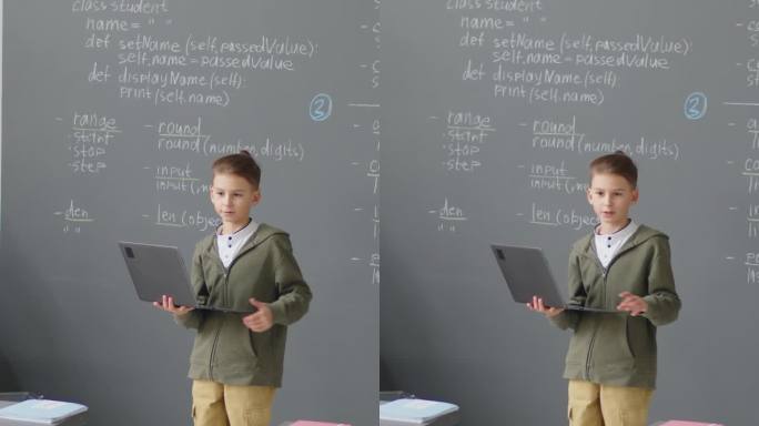 小男孩在教室里拿着笔记本电脑做报告