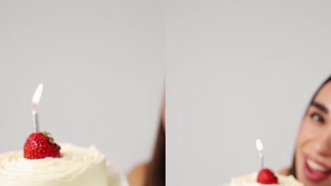 有草莓和蜡烛的蛋糕特写。这个女孩手里拿着一个白色背景的节日蛋糕。垂直视频。生日庆祝活动