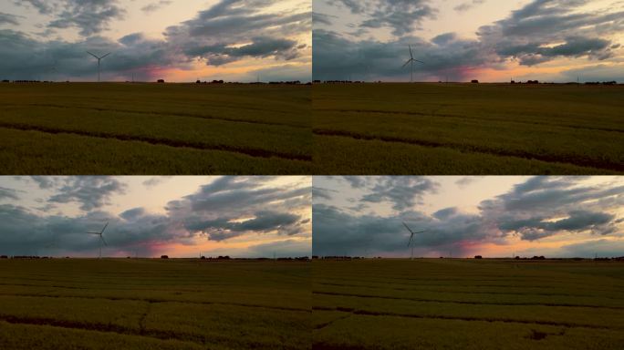 大型风力涡轮机的旋转叶片产生绿色能源，在傍晚日落与雨云的野外鸟瞰图