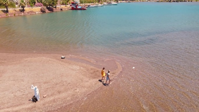 在土耳其地中海沿岸美丽的粉色沙滩上，一对可爱的游客在明亮美丽的风景上漫步。