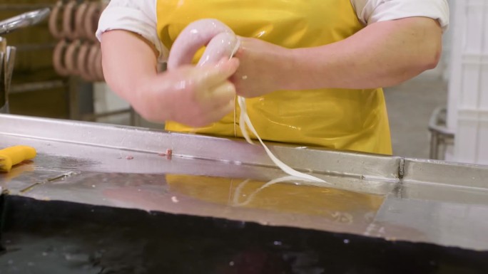 加工香肠的女工在肉厂用绳子固定末端。