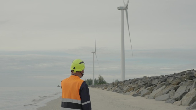 在泰国南部，一名男工程师正在使用智能手机检查海上风力涡轮机农场的指令。风力发电机组，绿色能源，环境可