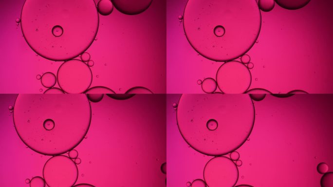 粉红色的油珠飘浮在水面上。粉彩泡沫的背景。橙色背景的油滴。