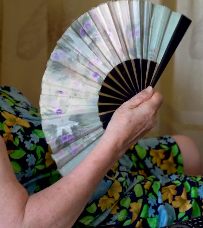 老妇人在用扇子一位老人在家里夏天炎热