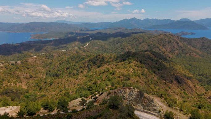 空中无人机拍摄的马尔马里斯半岛美丽的风景，山脉和丘陵，绿色的树林和弯弯曲曲的道路。环绕着爱琴海和地中