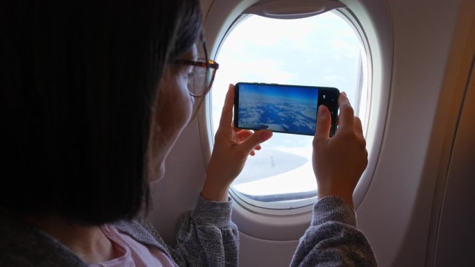 一名年轻女子正在拍飞机窗外的风景