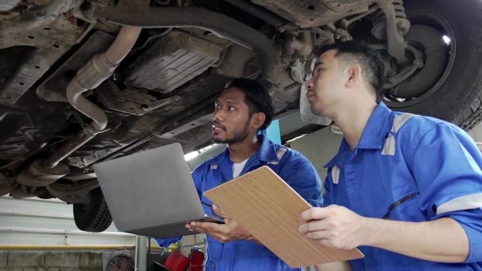 汽车修理工和团队检查汽车损坏部件的状况，在汽车修理厂诊断和修理汽车，汽车技师维修售后服务的概念。