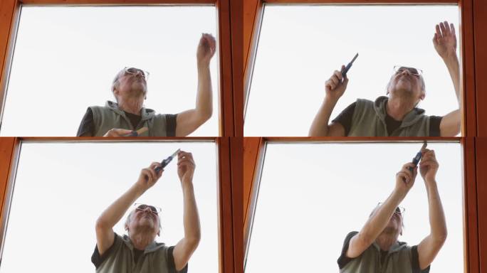 一个戴着眼镜、扎着马尾辫的男人正在剪掉阳台门上旧的硅胶垫圈