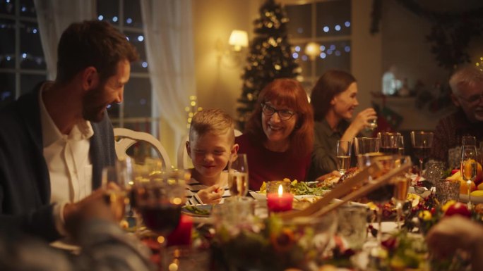 家人、孩子、朋友和年轻夫妇聚在家里度过一个欢乐的圣诞之夜。不同的人享受美味的火鸡大餐，分享温馨的对话