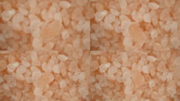 一粒粉红色的海盐落在一簇盐上，微距放大，俯视视图。