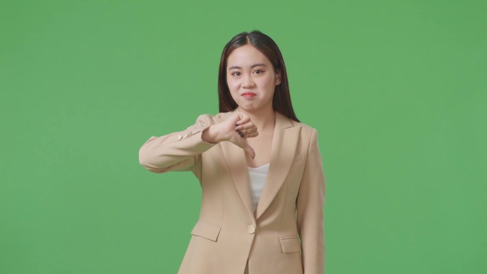 亚洲女商人站在绿幕演播室时竖起拇指向下的手势