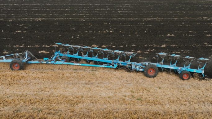 在田地里，在拖拉机后面移动的有支撑轮的可逆犁。耕地是为了播种。高生产力的反向犁工作在慢动作。农业，为