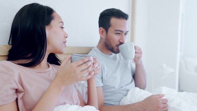 爱，早晨，一对夫妇在卧室里一起喝茶，而在家里放松周末。咖啡，微笑或快乐的男人和女人在床上聊天在他们的