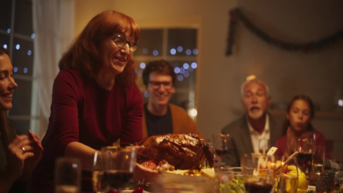 一位中年妇女将火鸡端上餐桌的肖像，带着孩子的令人兴奋的家庭。朋友们欢聚一堂，享用美味的烤大餐。慢动作