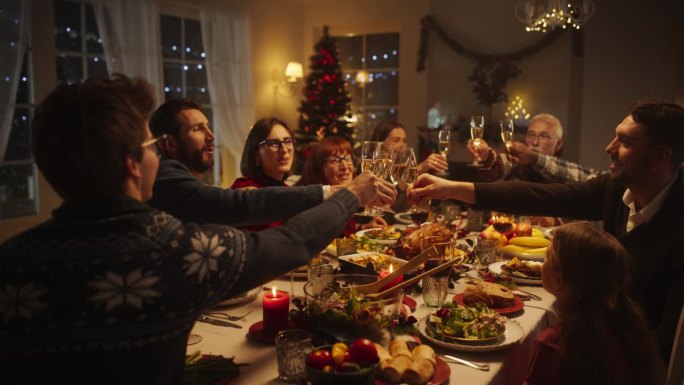 与父母、孩子和朋友在家共进圣诞晚餐。多元文化的家庭举起香槟酒杯，举杯祝酒，晚上用美味的火鸡大餐庆祝节