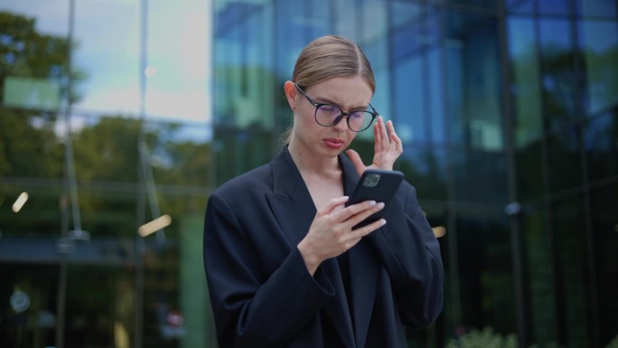 时尚的女商人在她的智能手机上读着一条痛苦的信息。女孩感到不快乐并经历负面情绪，在网上交易中遭受重大经