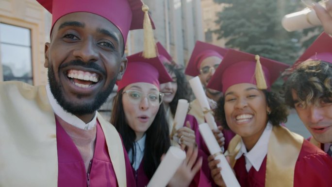 男男女女戴着毕业帽，穿着毕业服，在网上视频通话，看着展示文凭的摄像机