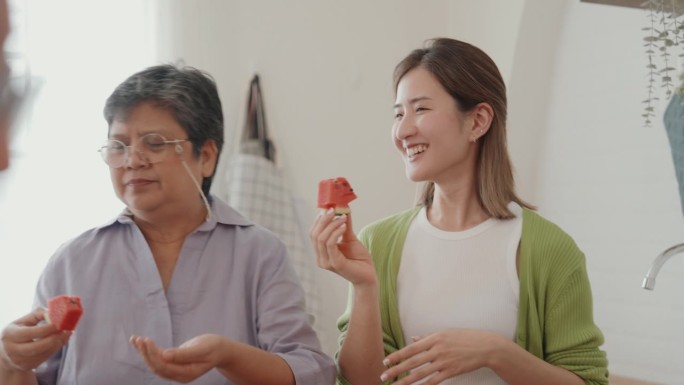 快乐的亚洲年轻女性和老人在家一起做素食:一个快乐的聚会，分享笑声和自制的幸福。