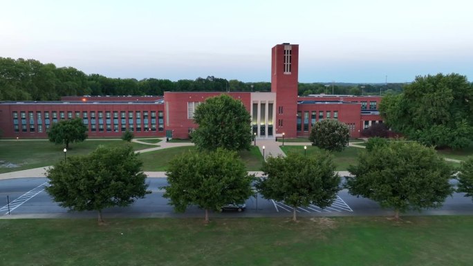 日落时分的美国高中。卡车航拍的外部前门的照片。大型砖砌教育大楼。