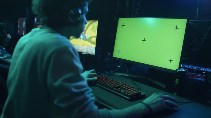 男性顾客在赛博俱乐部玩绿色屏幕的电子游戏
