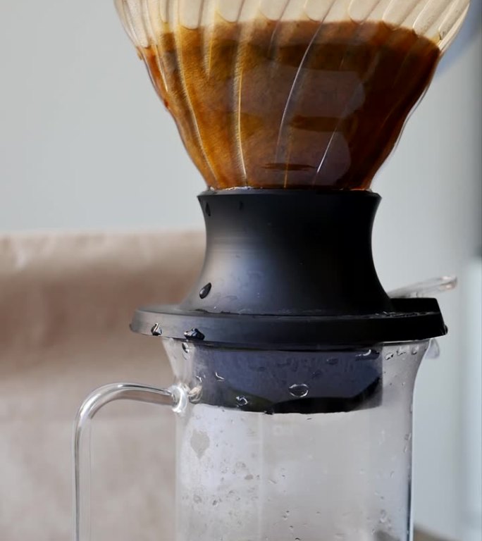 在烹饪过程中，将沸水倒入滴漏式咖啡机的漏斗杯过滤器的垂直视频。将热水倒入咖啡粉中冲泡天然咖啡