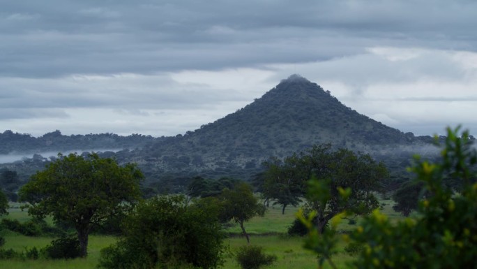 在多云的天空下，坦桑尼亚群山环绕着绿树