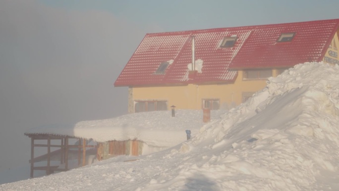 雪堆在山上有一座两层楼高的房子。