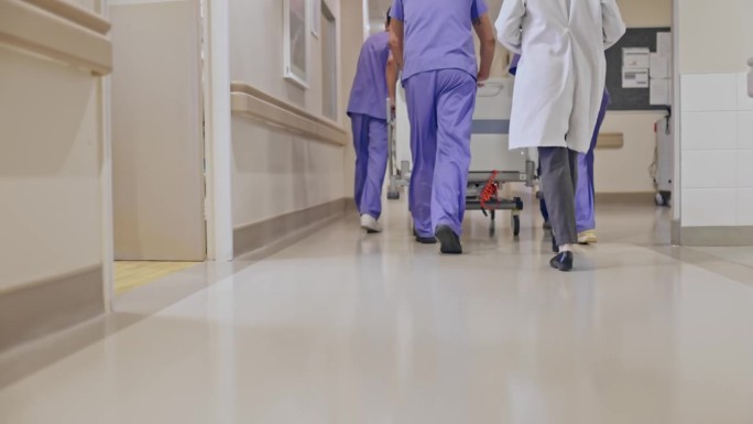 医护人员和医生在医院走廊推轮式病床的后视图