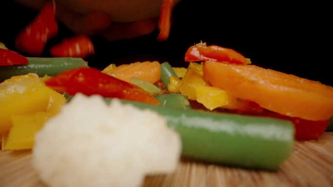 切片和煮熟的蔬菜以慢镜头落在木桌上。