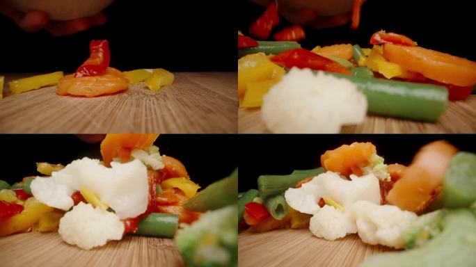 切片和煮熟的蔬菜以慢镜头落在木桌上。