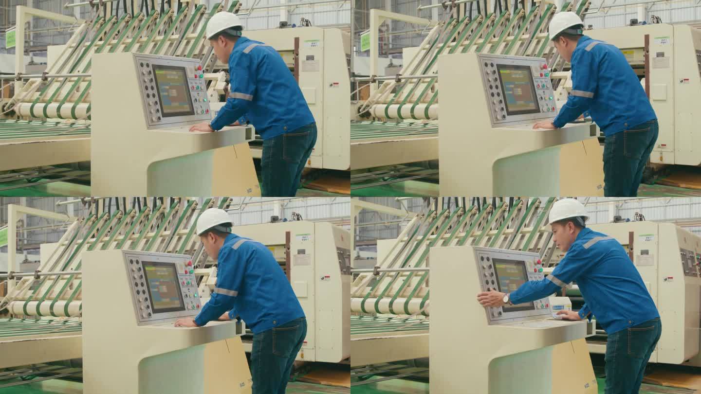 专业的亚洲男性工业工程师在制造工厂操作机器键盘。在制造厂或生产厂工作。