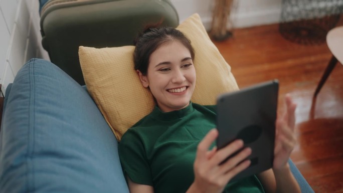 连接幸福:不同的女人微笑着在家里舒适的沙发上享受科技。