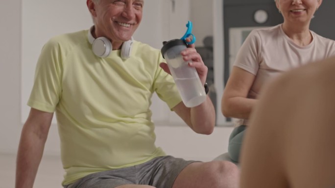 老人在集体健身后与教练聊天喝水